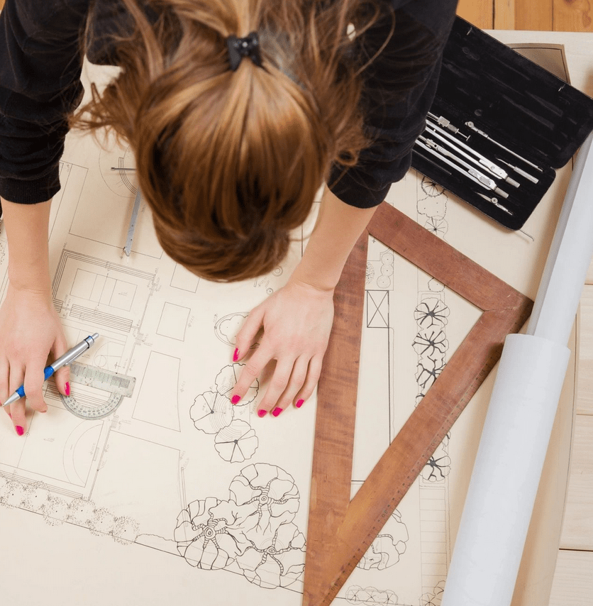 A woman is working on a drawing of a house.