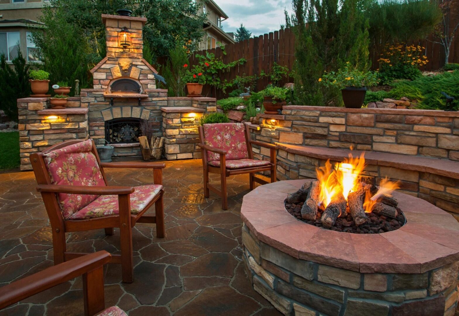 A patio with a fire pit and chairs.