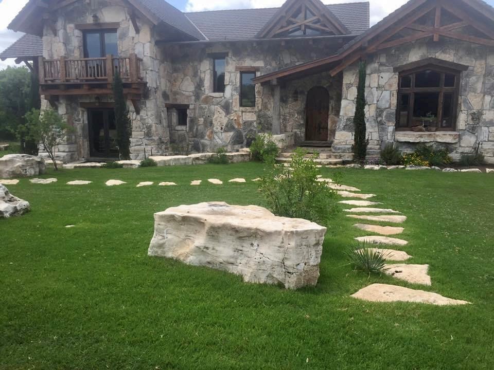 stone walkway going to a house with a beautiful stone exterior