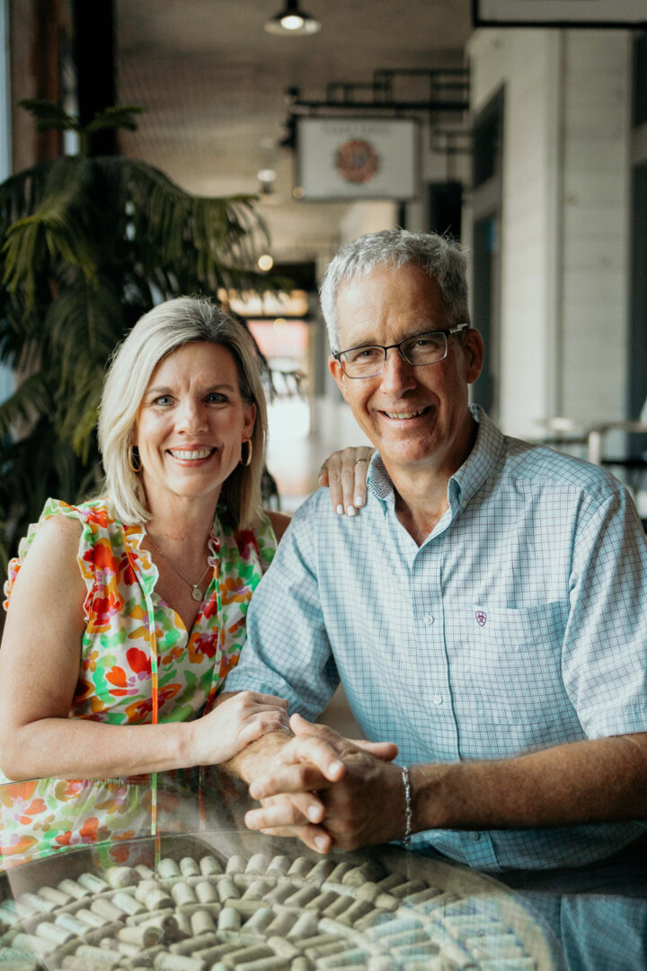 A man and woman posing for a photo in front of a table.